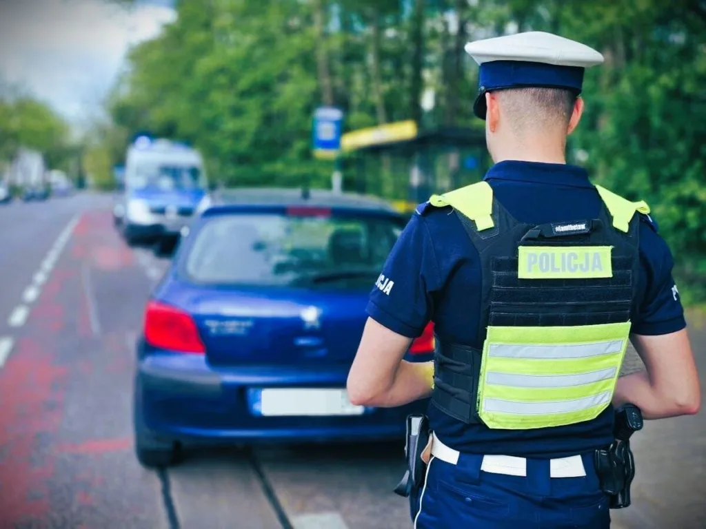 policjant w odblaskowej kamizelce stojący obok zatrzymanego pojazdu